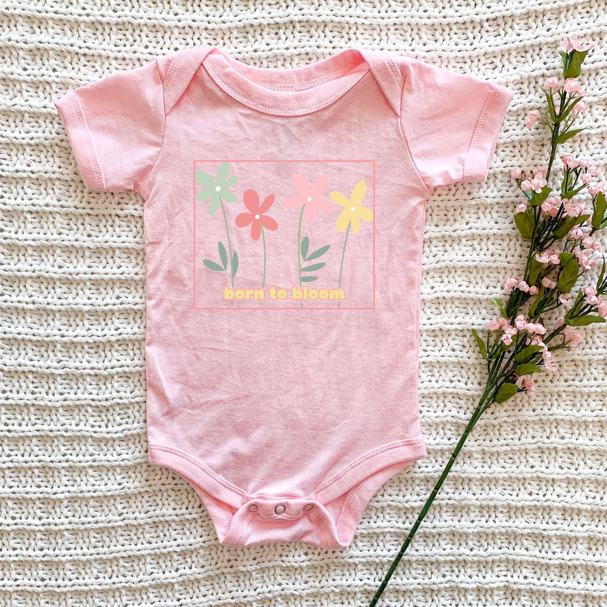 Soft pink infant bodysuit with colorful Born to Bloom flower graphic.