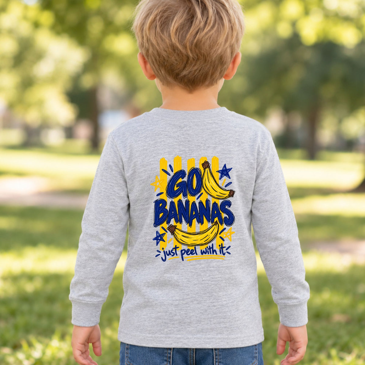 Toddler wearing a heather Go Bananas long sleeve tee, back view showing the full banana design with “Just Peel With It.”