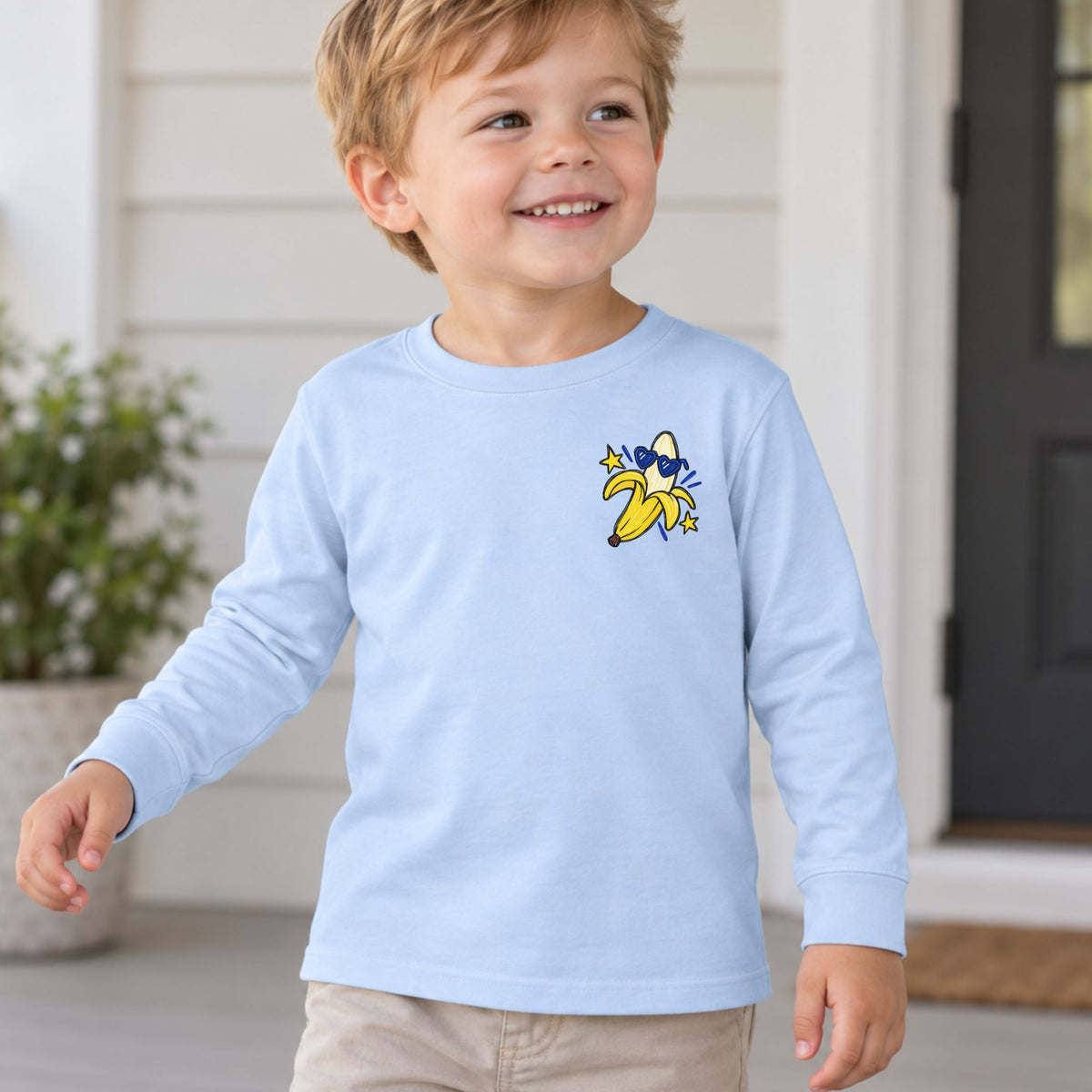 Toddler wearing a light blue Go Bananas long sleeve tee, front view showing the banana left-chest design.