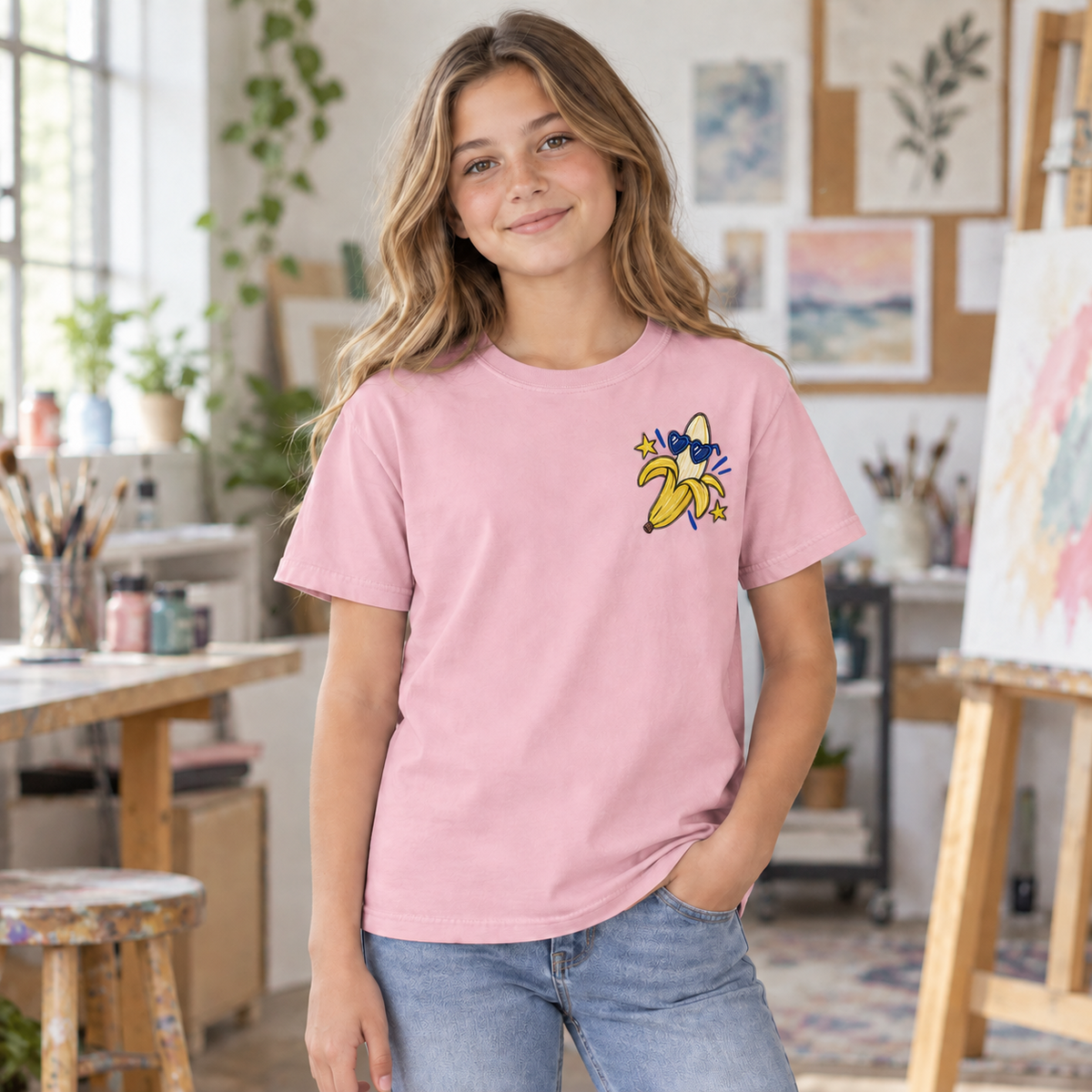 Youth wearing a soft pink Go Bananas tee, front view showing the banana left-chest design.