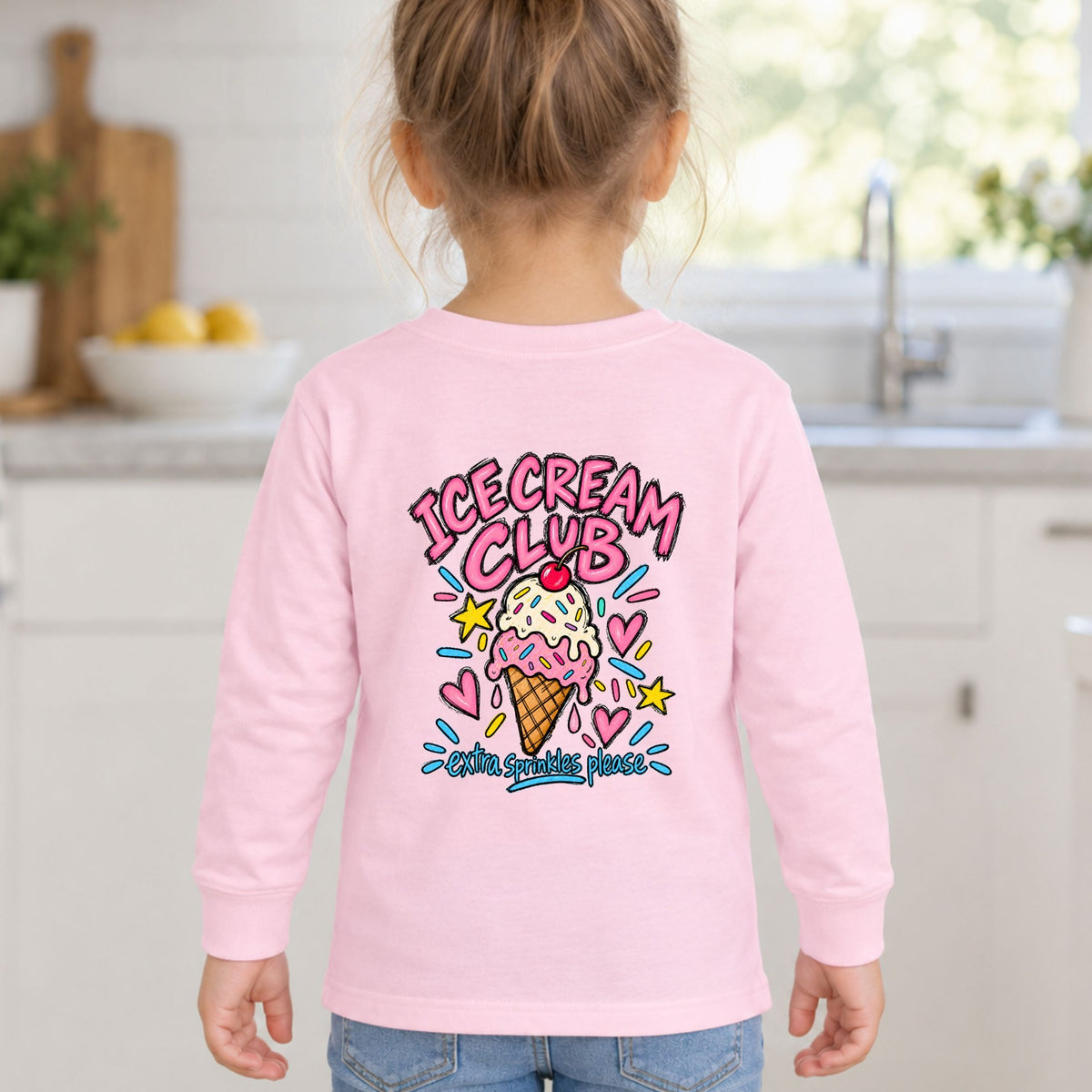 Girl wearing a pink Ice Cream Club toddler long sleeve tee, back view showing the Extra Sprinkles Please design.