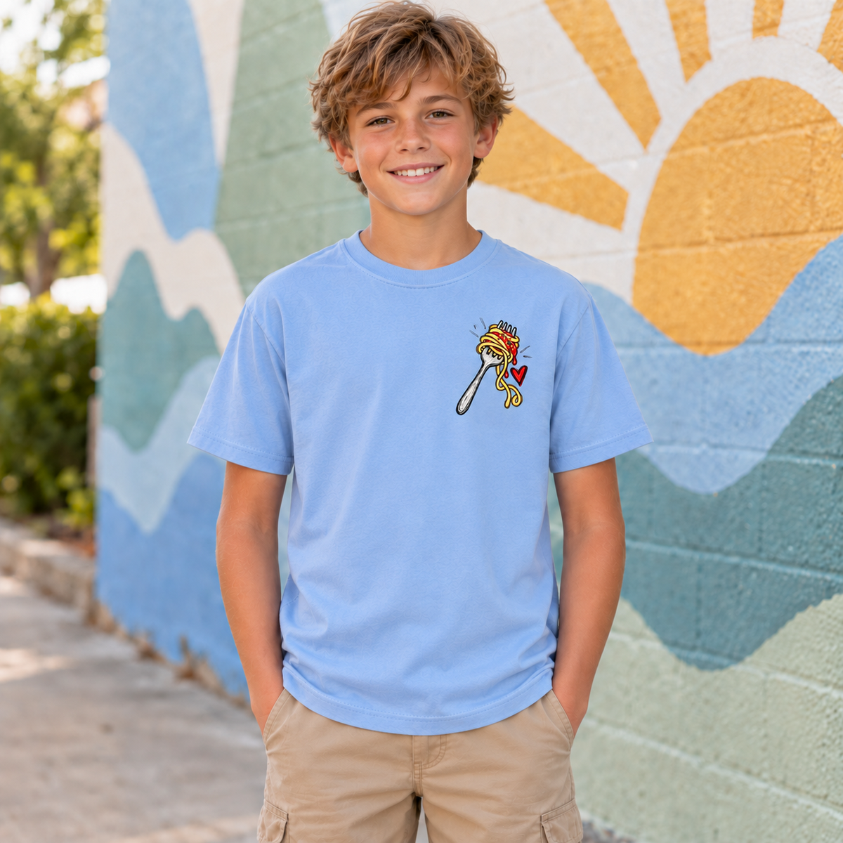 Youth model wearing a light blue No Regretti More Spaghetti short sleeve tee, front view showing the forkful of spaghetti left-chest design.
