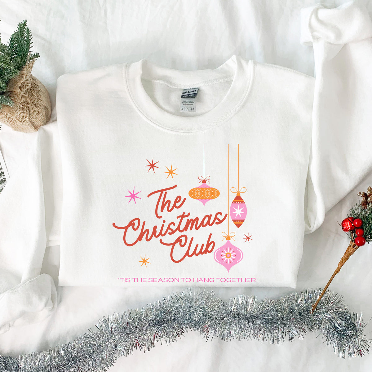 White The Christmas Club ’Tis the Season to Hang Together adult crewneck sweatshirt in a Christmas flat lay.